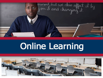 A teacher smiles at his desk. A ribbon that says 