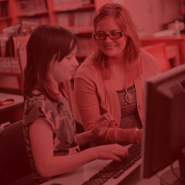 Student teacher mentoring a student on a computer