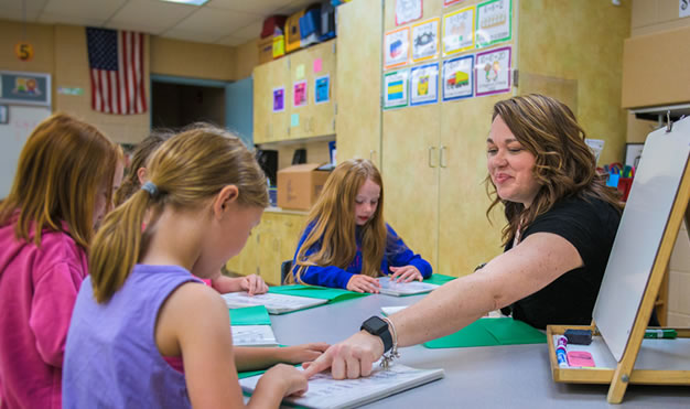 Teacher pointing at item on desk in front of student