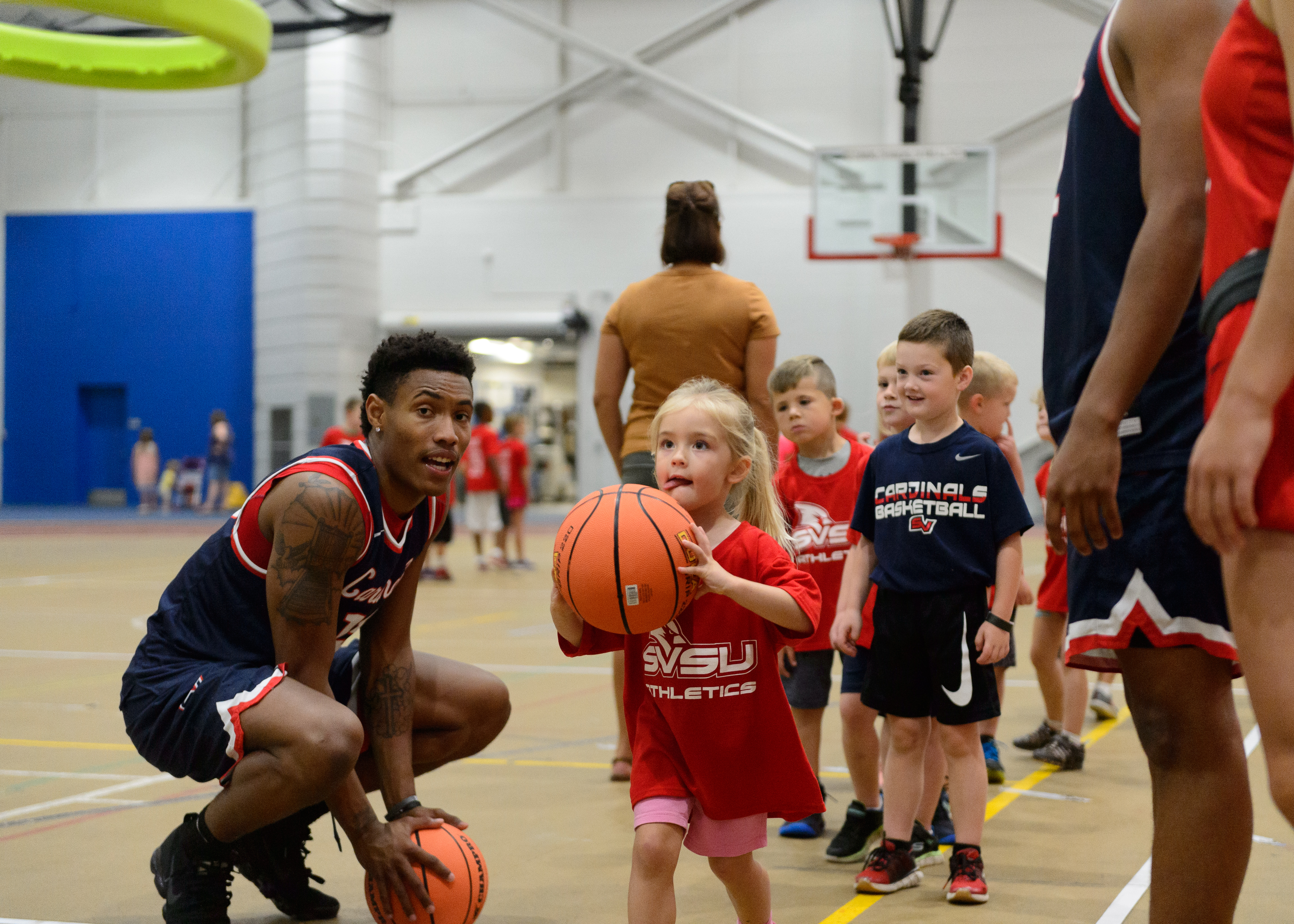 Student athlete working with local youth to shoot a basketball