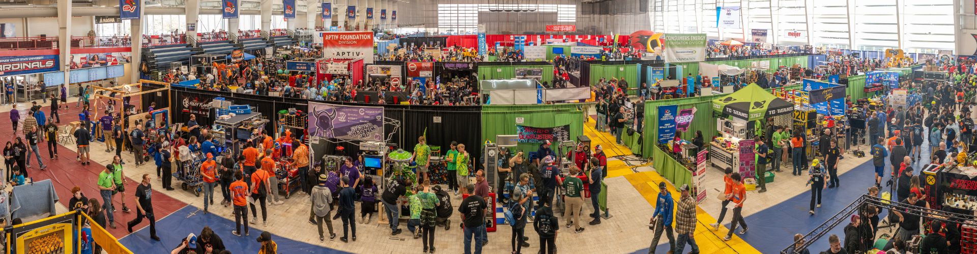 many booths for robotics teams in large open area with people walking around