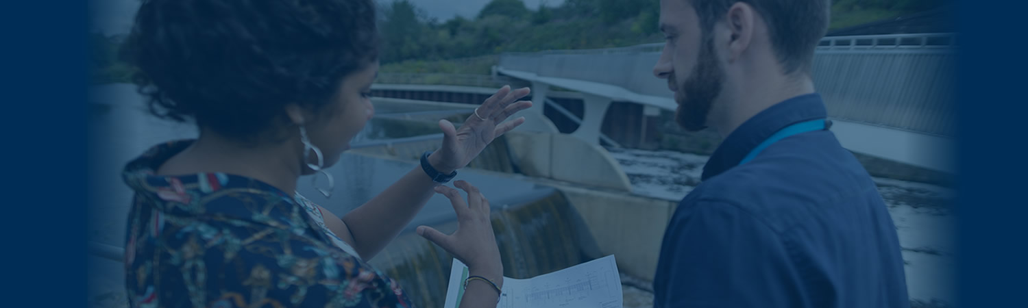 Two people evaluating water quality near dam