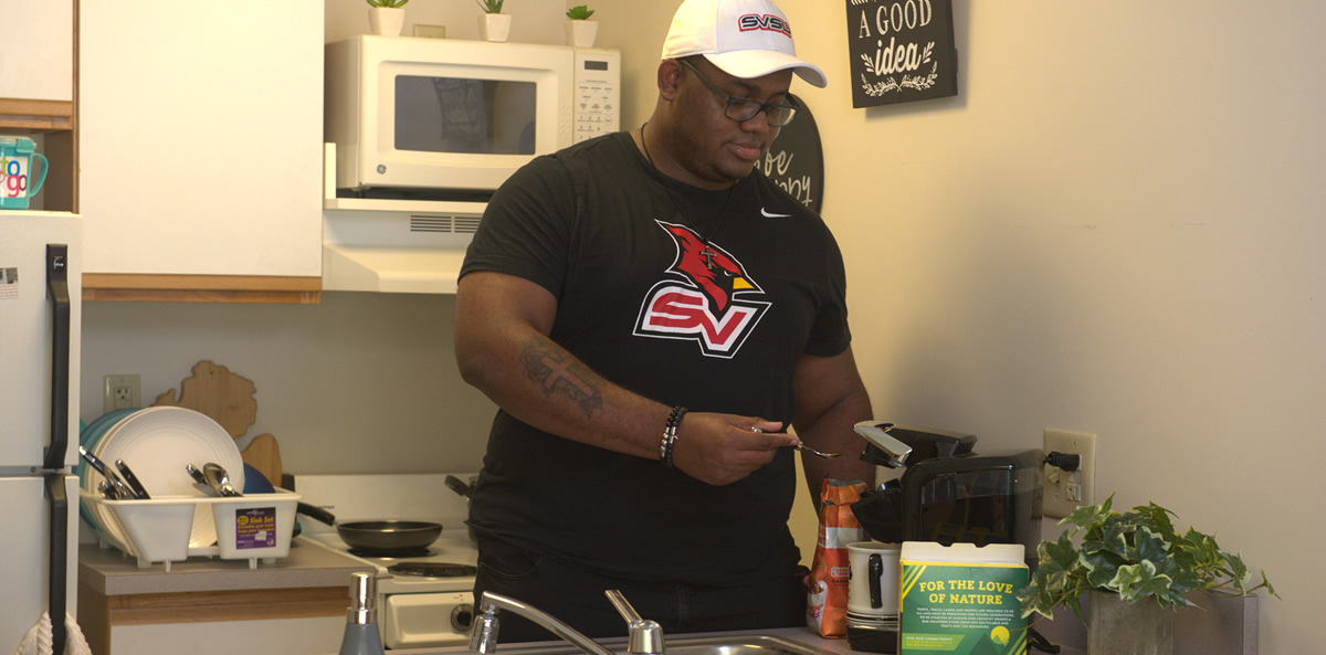 Student making coffee in housing unit