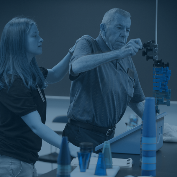 An OT student works with a patient using lab equipment