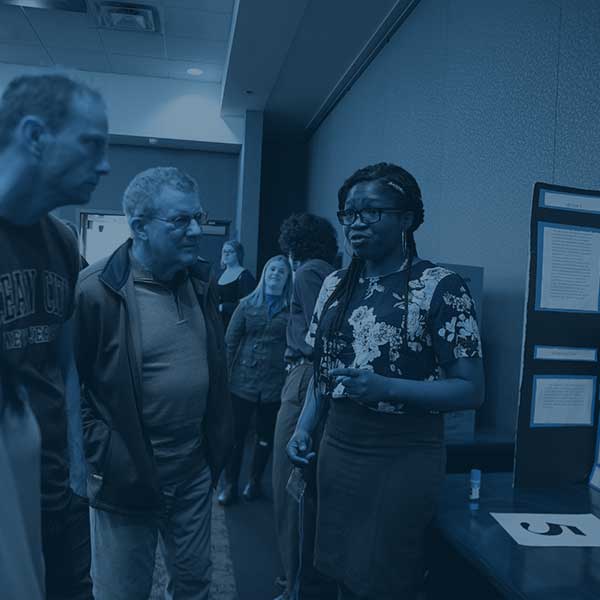 young woman student presenting research to two men