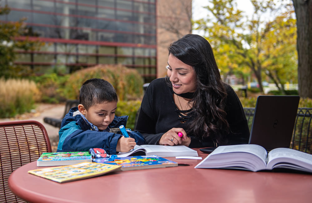 Social work student sitting with a young child, coloring