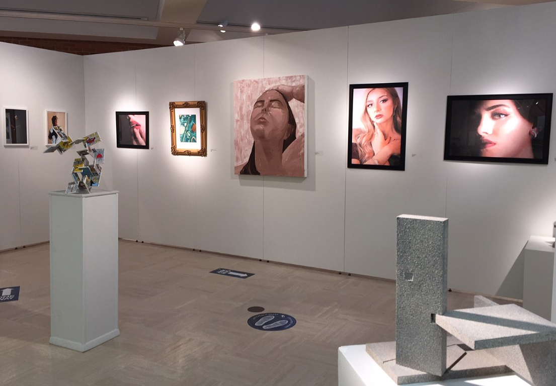 student artwork visible from the outside of gallery featuring paintings, sculptures and photographs